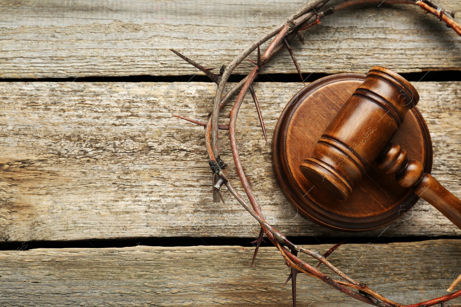 Photo of Crown of thorns and judge gavel on wooden table, flat lay. Space for text