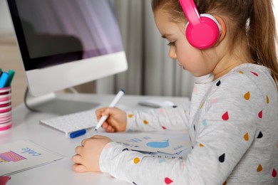 Little girl learning English indoors at online lesson, closeup