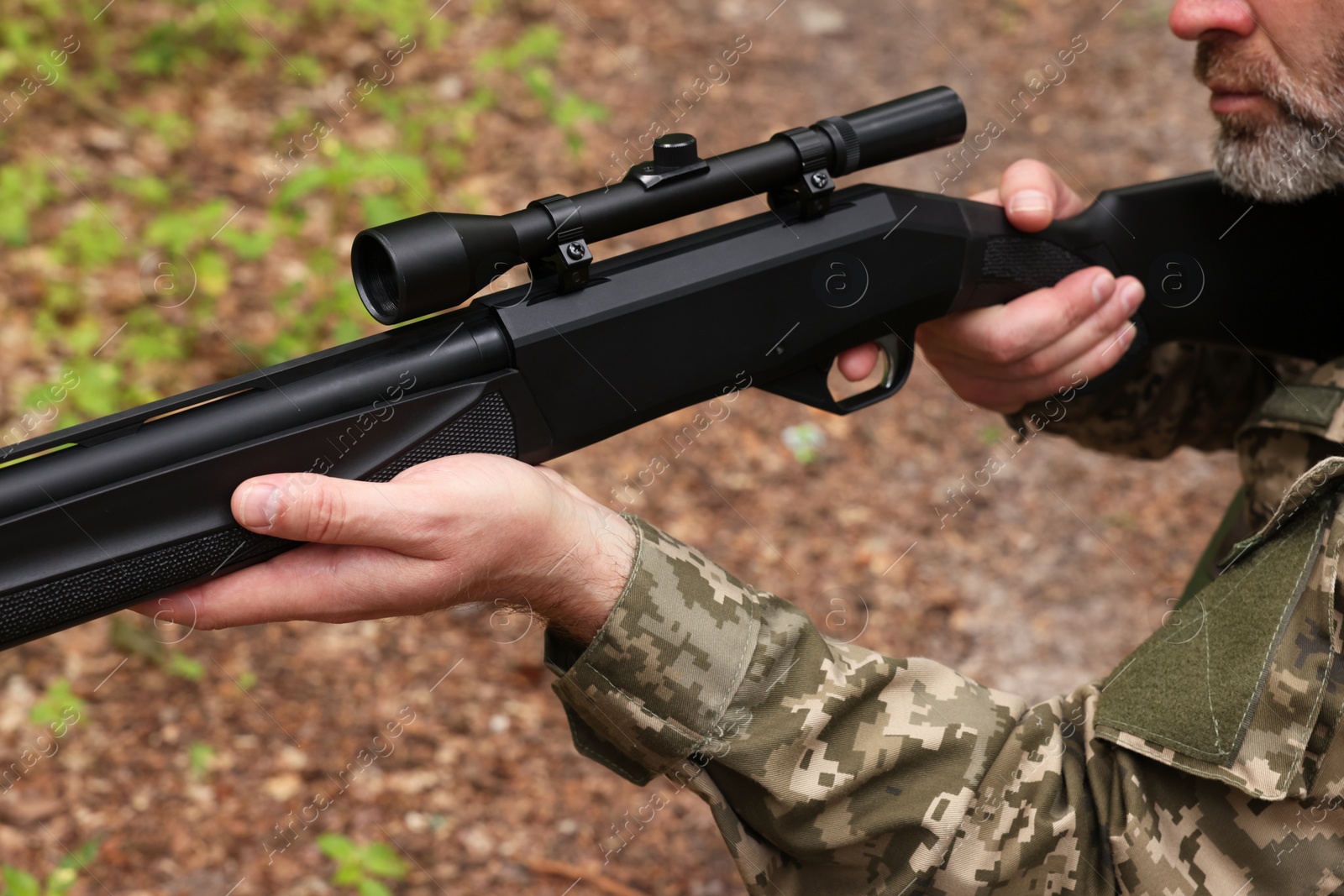 Photo of Man wearing camouflage and aiming with hunting rifle outdoors, closeup