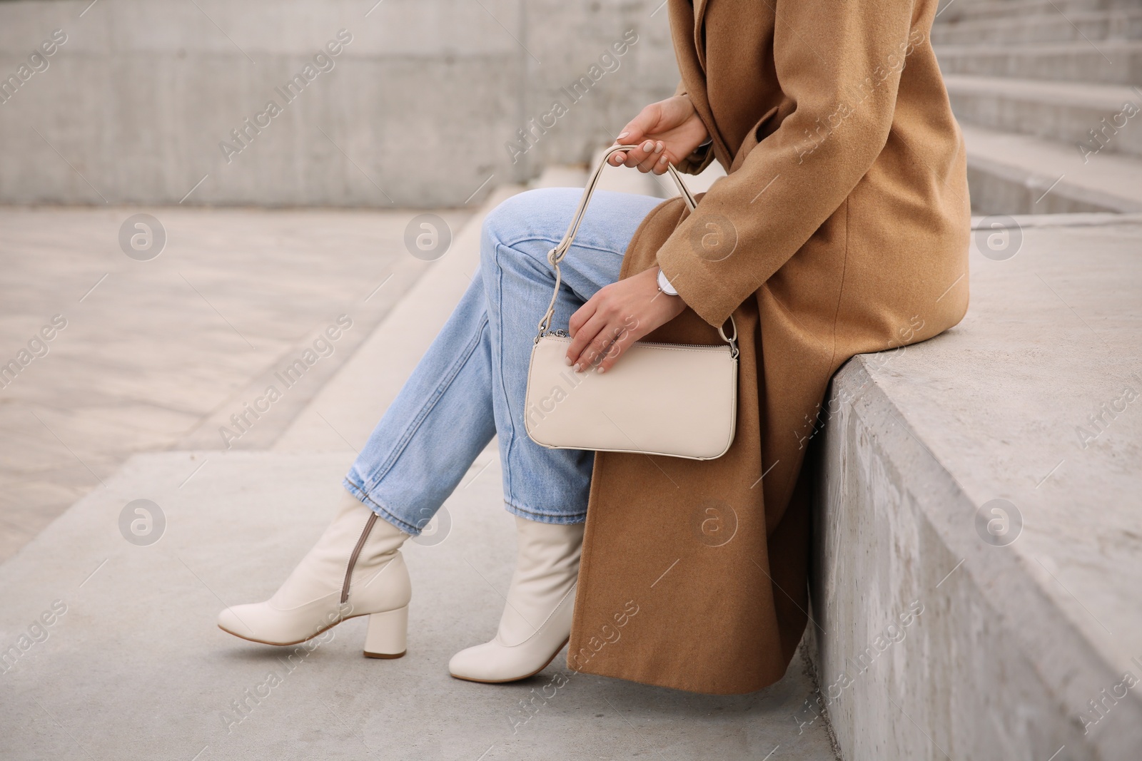 Photo of Stylish woman with trendy beige bag on stairs outdoors, closeup