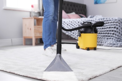 Photo of Mature man hoovering carpet with vacuum cleaner at home