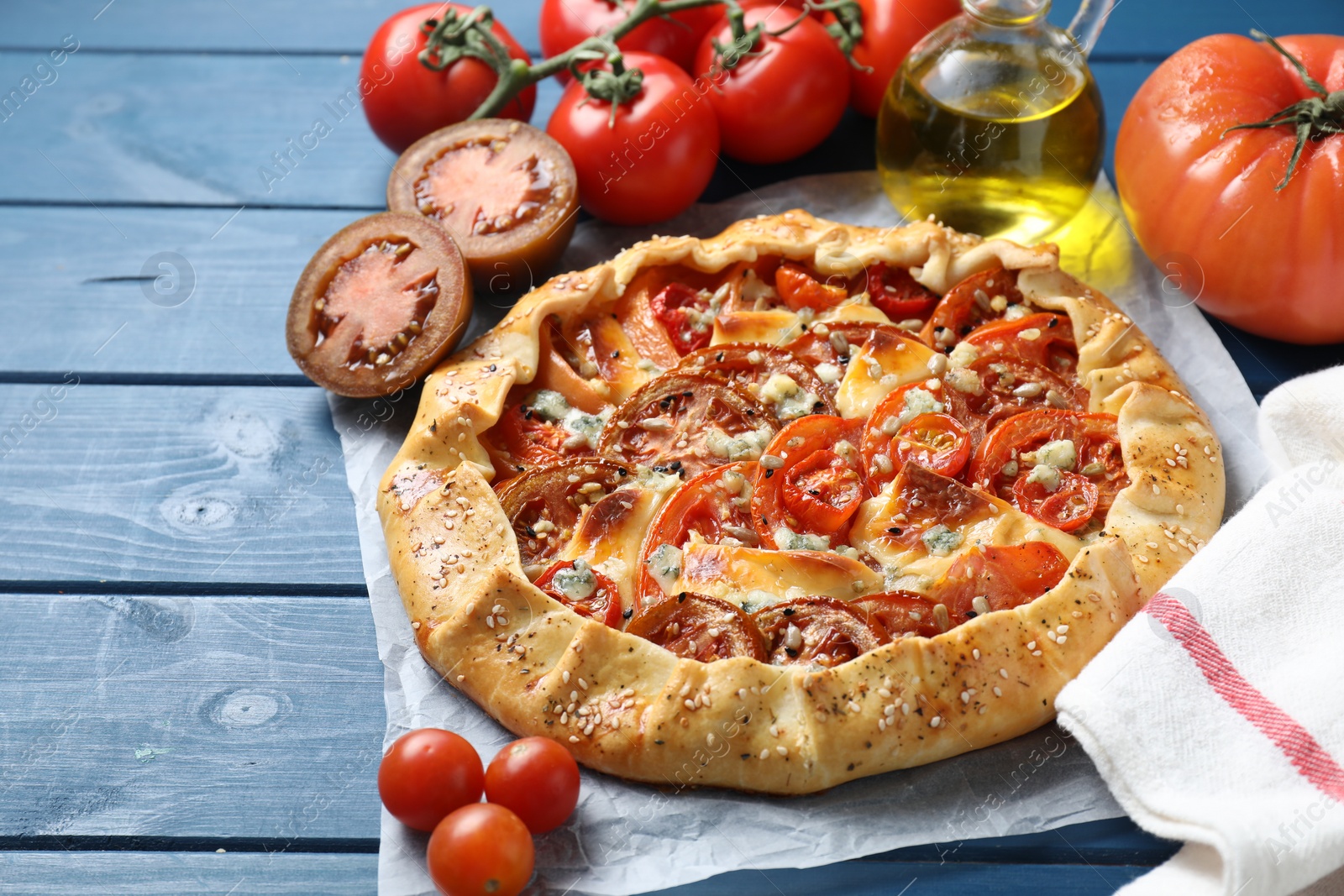 Photo of Tasty galette with tomato and cheese (Caprese galette) on blue wooden table, closeup