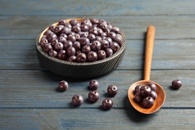 Photo of Plate and spoon with fresh acai berries on wooden table