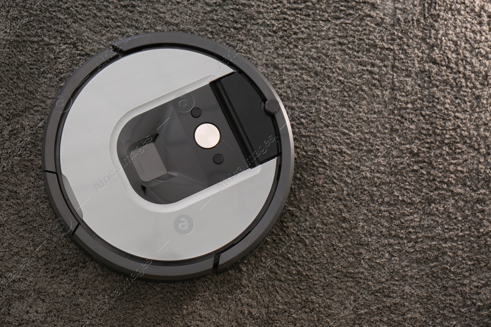 Photo of Modern robotic vacuum cleaner on dark carpet, top view. Space for text