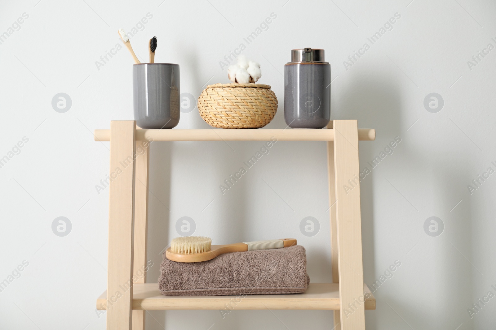 Photo of Wooden shelving unit with toiletries near white wall indoors. Bathroom interior element