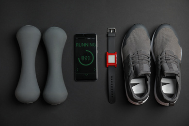 Photo of Flat lay composition with fitness equipment and smartphone on black background