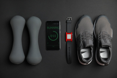 Flat lay composition with fitness equipment and smartphone on black background