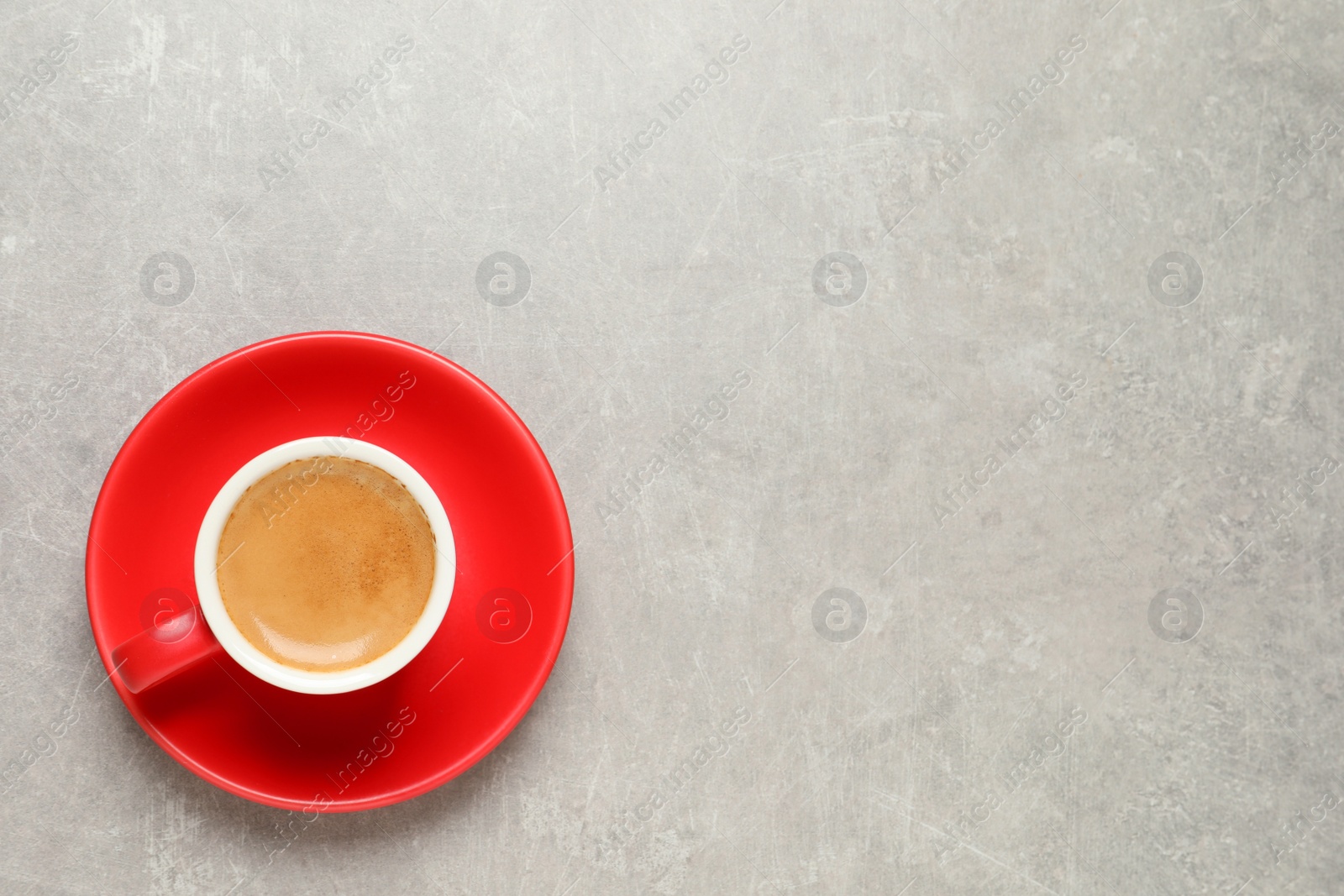 Photo of Aromatic coffee in red cup on light grey background, top view. Space for text