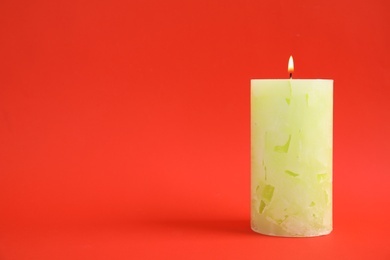 Alight wax candle on color background. Space for text