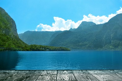 Image of Beautiful view of mountains and wooden pier near river on sunny day