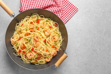 Photo of Frying pan with spaghetti and shrimps on light background, top view