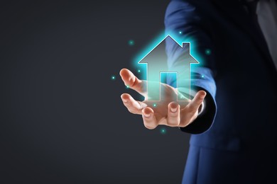 Mortgage rate. Man holding illustration of house on black background, closeup. Space for text