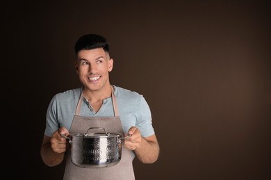 Photo of Happy man with pot on brown background, space for text