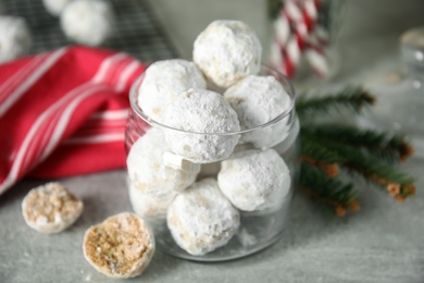 Photo of Tasty snowball cookies in glass jar on grey table. Christmas treat