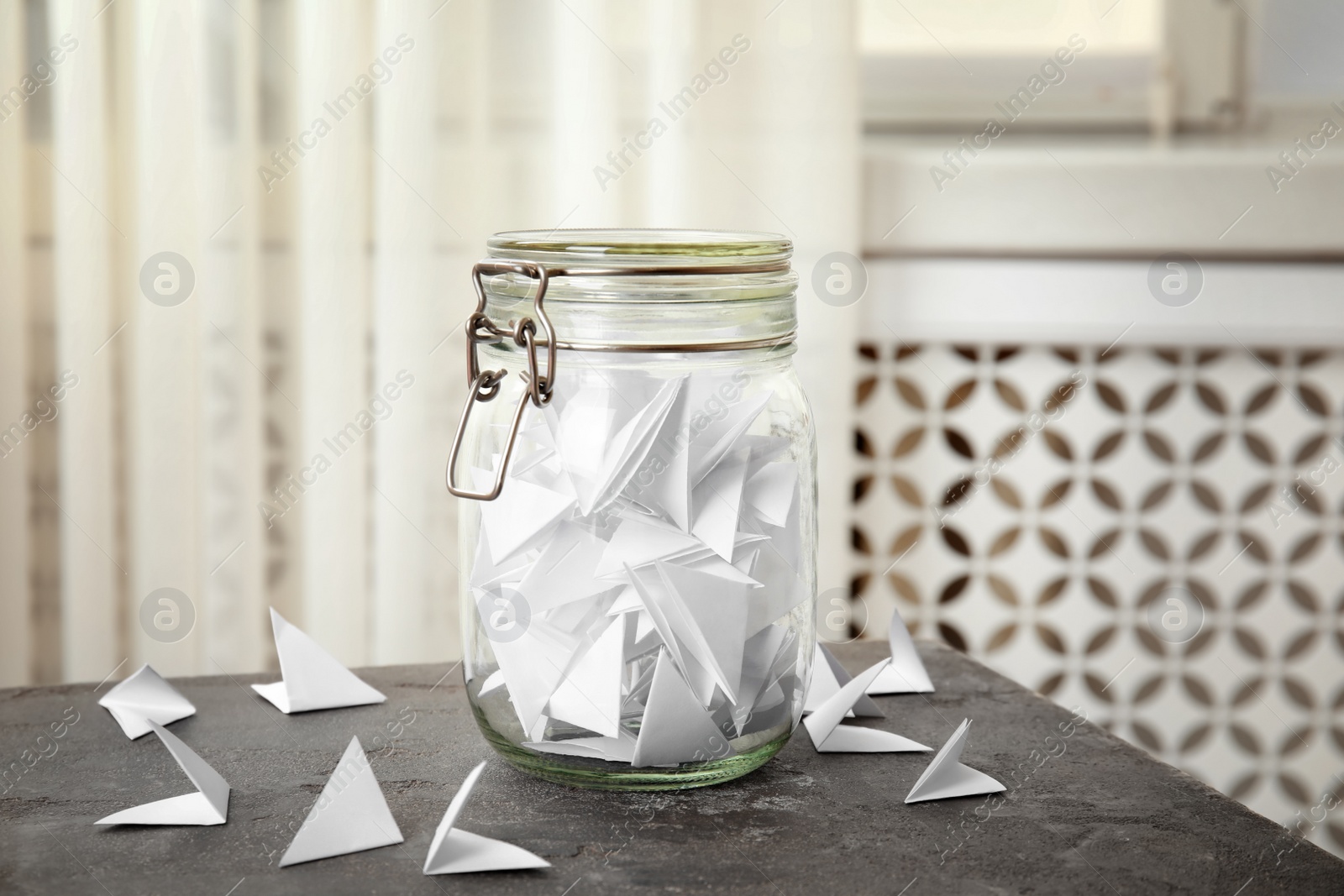 Photo of Paper pieces for lottery and glass jar on gray table