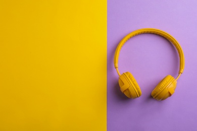 Wireless headphones on color background, top view. Space for text