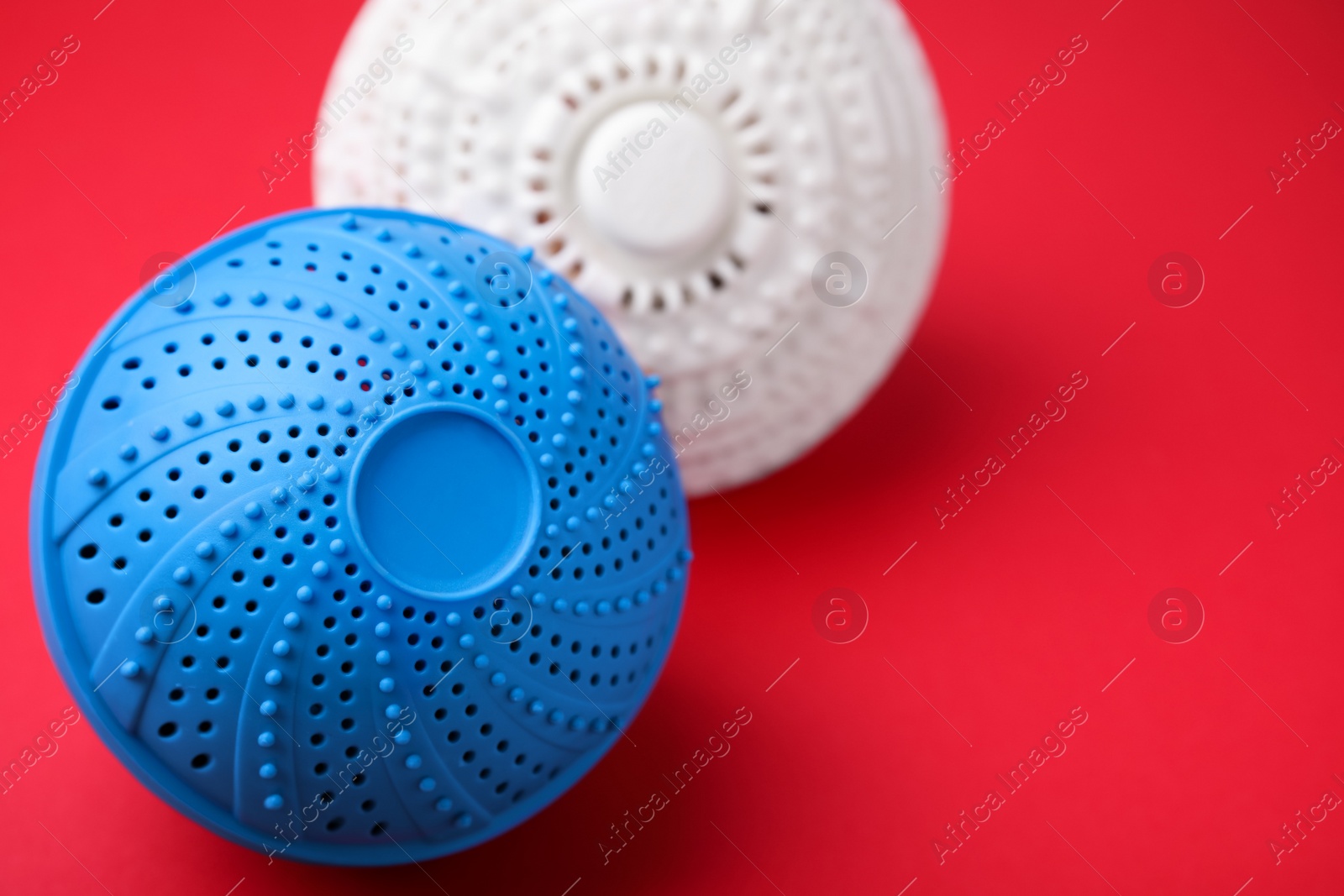 Photo of Laundry dryer balls on red background, closeup. Space for text