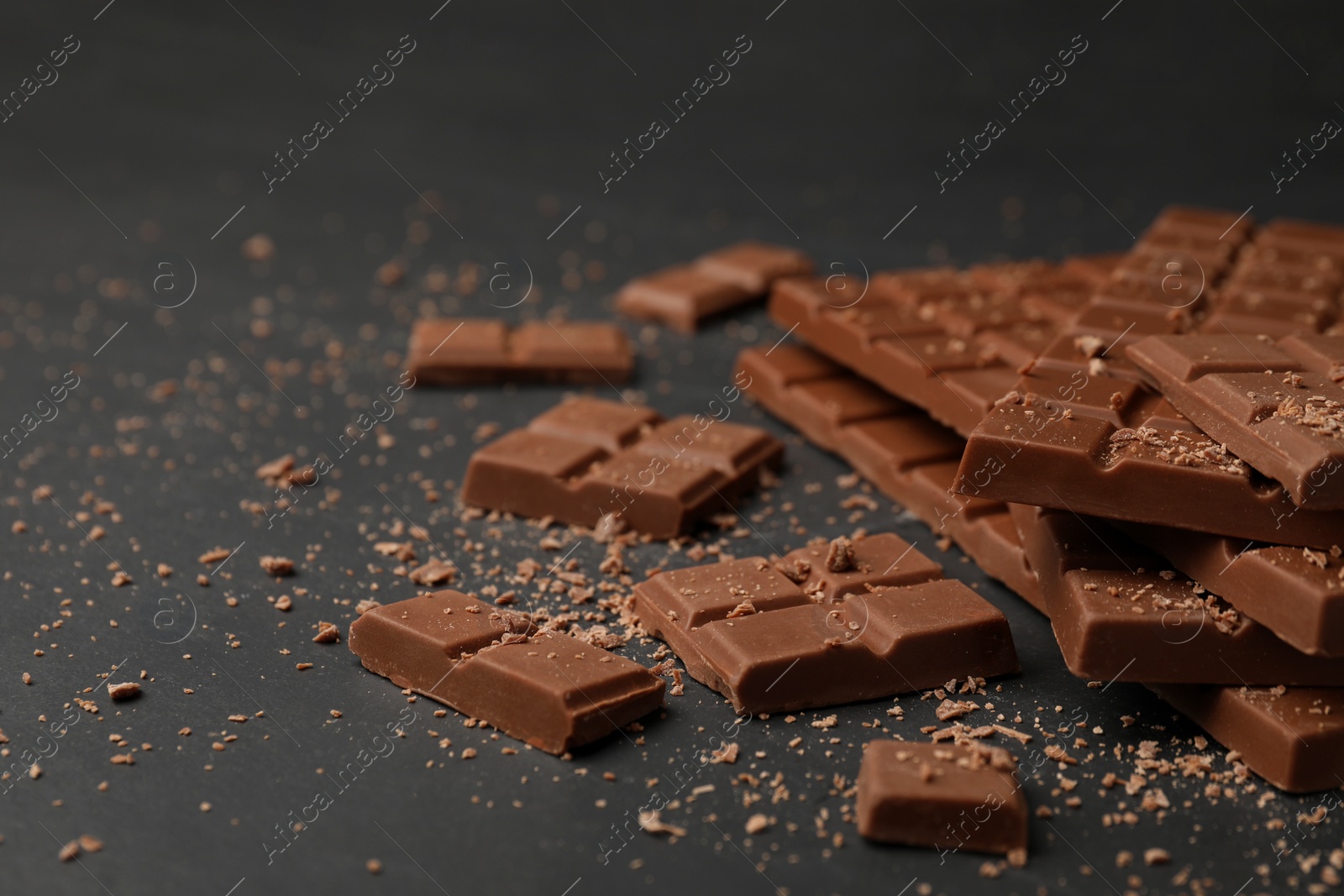 Photo of Pieces of tasty chocolate bars on grey table, space for text