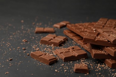 Pieces of tasty chocolate bars on grey table, space for text