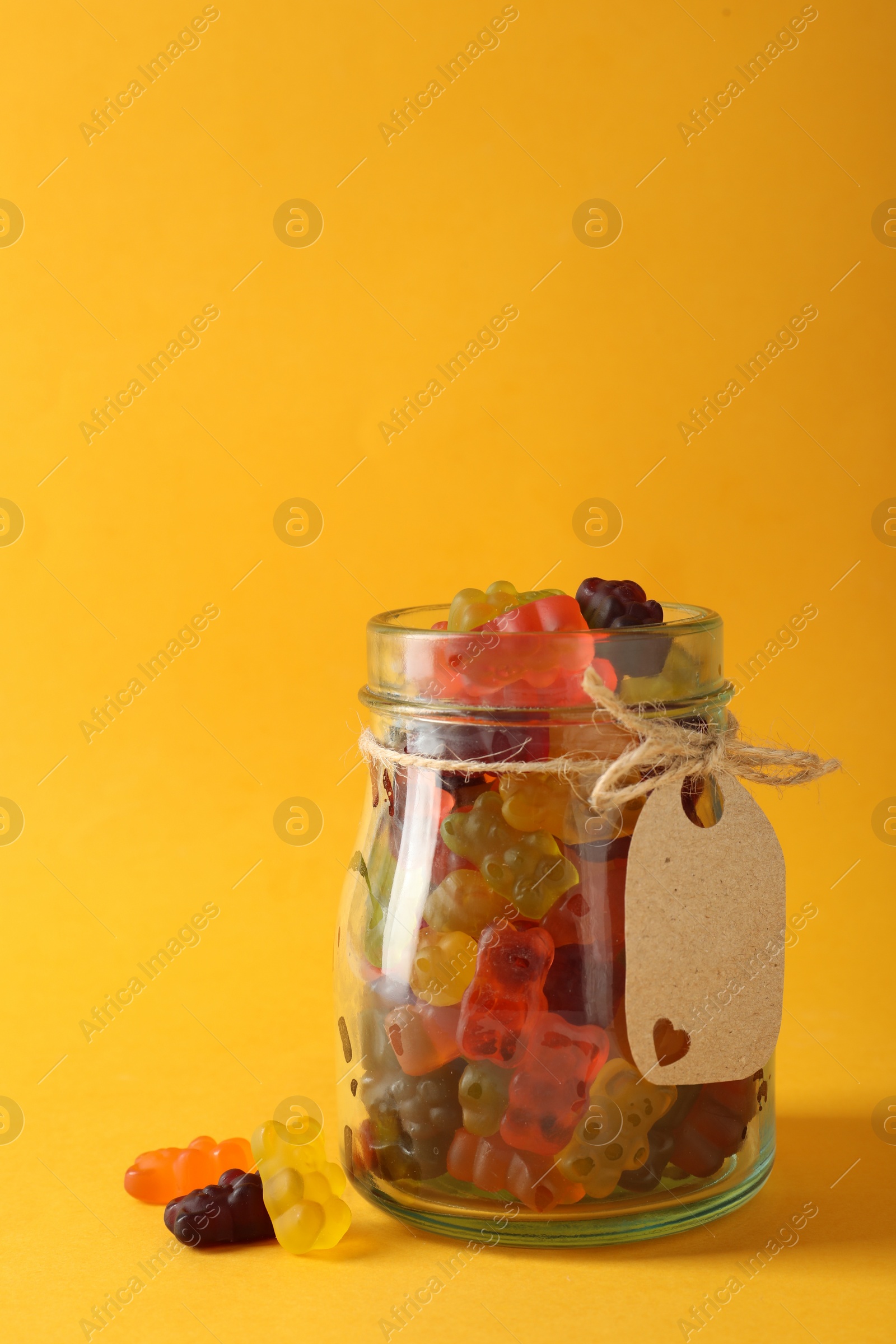 Photo of Delicious gummy bear candies on yellow background