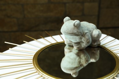 Photo of Stone frog figure with mirror on white table. Space for text