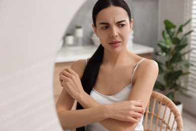 Woman with dry skin looking at mirror in bathroom