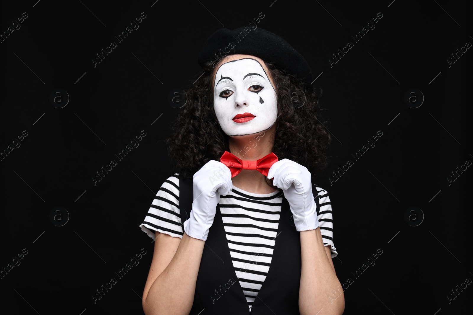 Photo of Young woman in mime costume posing on black background