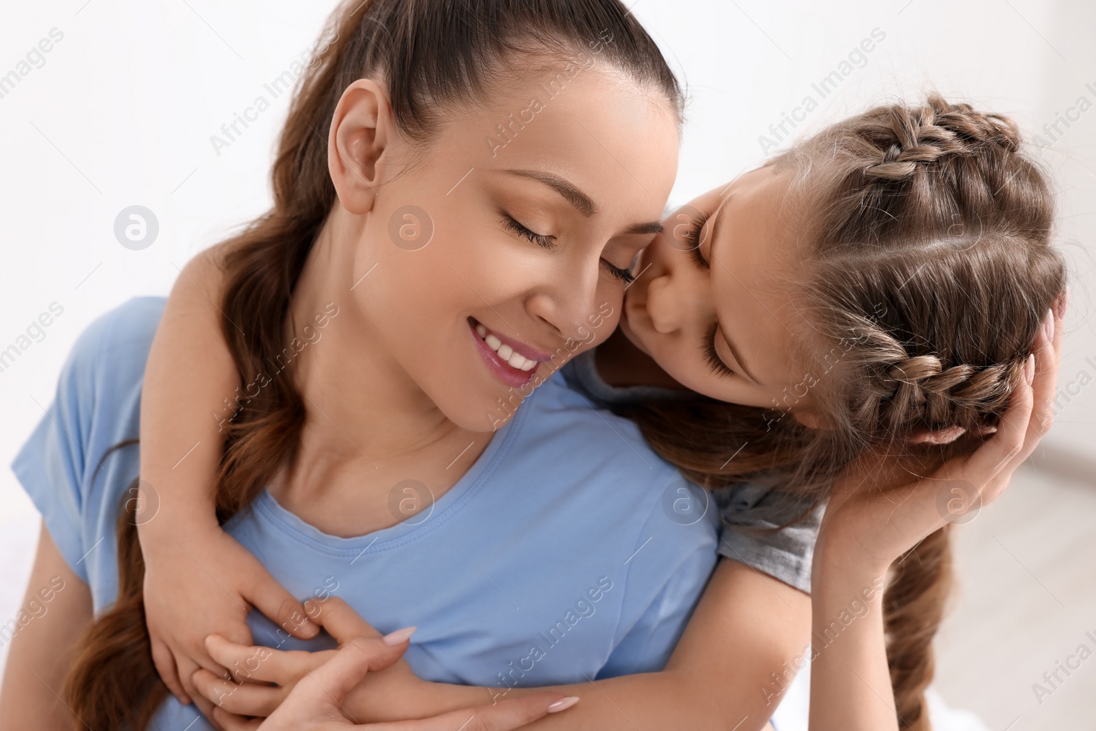 Photo of Cute daughter kissing and hugging her mom indoors
