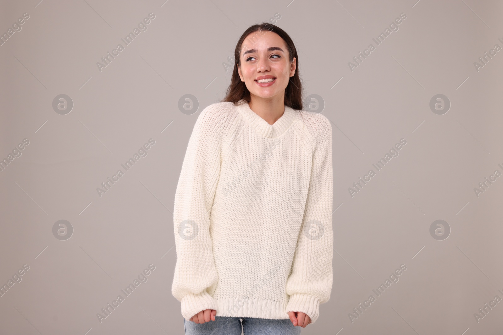 Photo of Beautiful young woman in stylish warm sweater on grey background