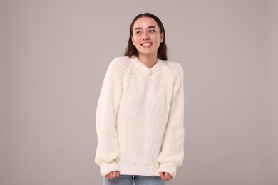 Photo of Beautiful young woman in stylish warm sweater on grey background