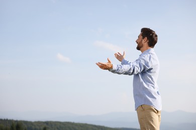 Photo of Feeling freedom. Happy man with wide open arms outdoors, space for text