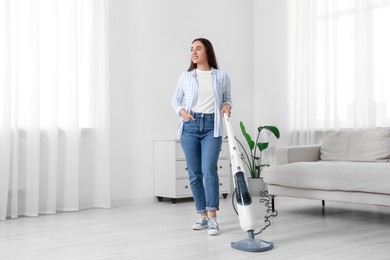 Happy woman cleaning floor with steam mop at home