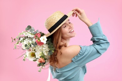 Photo of Beautiful woman in straw hat with bouquet of flowers on pink background