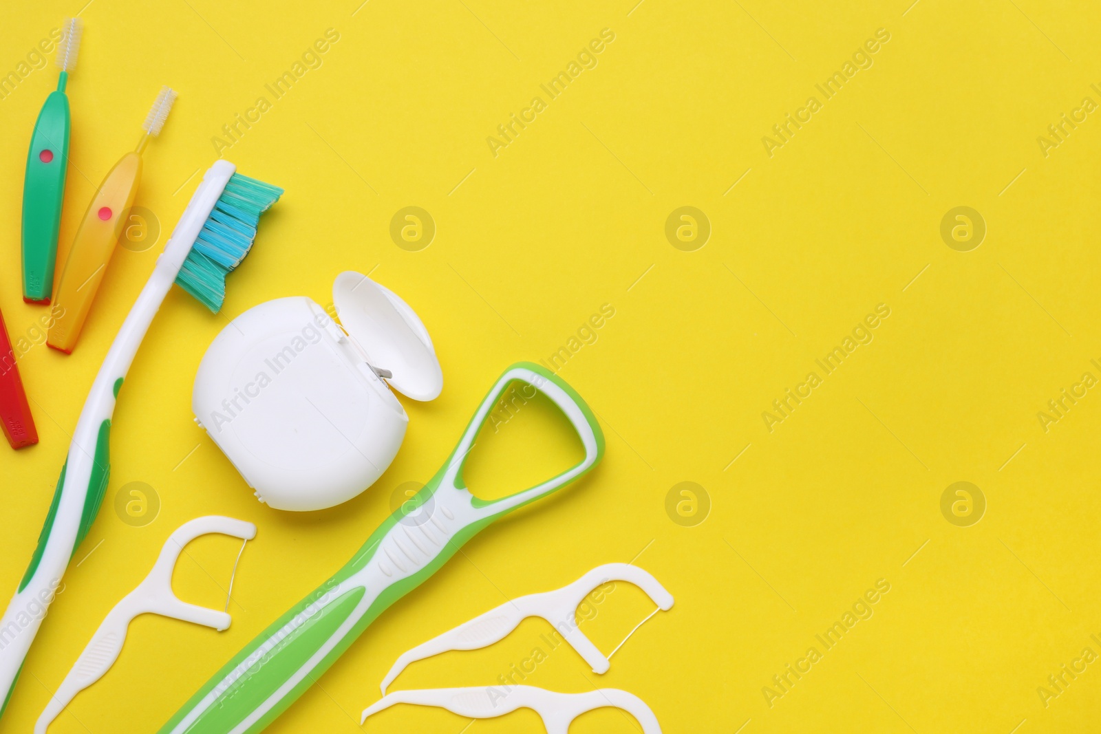 Photo of Tongue cleaner and other oral care products on yellow background, flat lay. Space for text