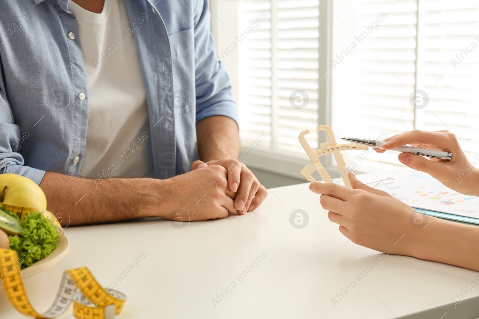 Photo of Young nutritionist consulting patient at table in clinic, closeup