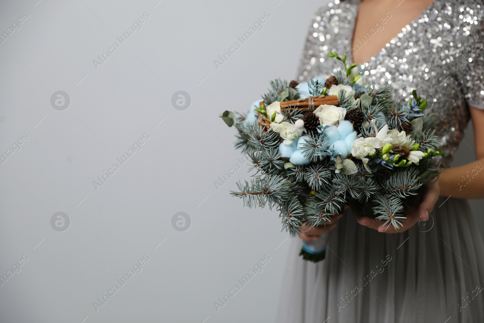 Photo of Bride holding beautiful winter wedding bouquet on light grey background, closeup. Space for text