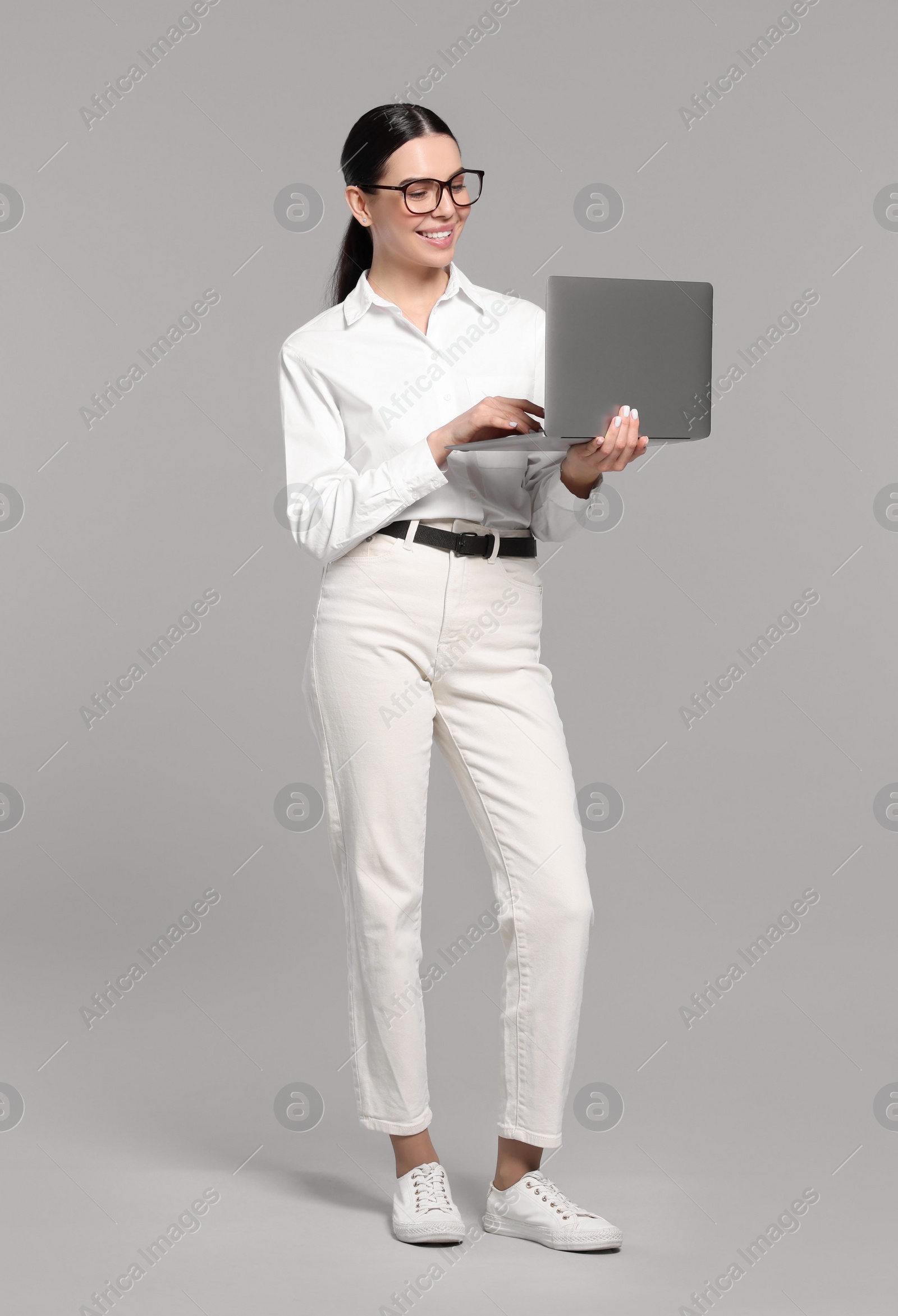 Photo of Happy woman using laptop on light gray background