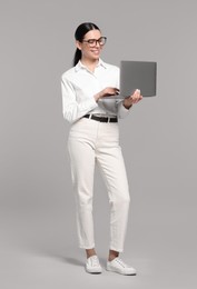 Photo of Happy woman using laptop on light gray background