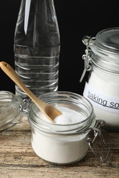 Photo of Baking soda, spoon and vinegar on wooden table