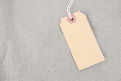 Photo of Cardboard tag on beige garment, top view. Space for text