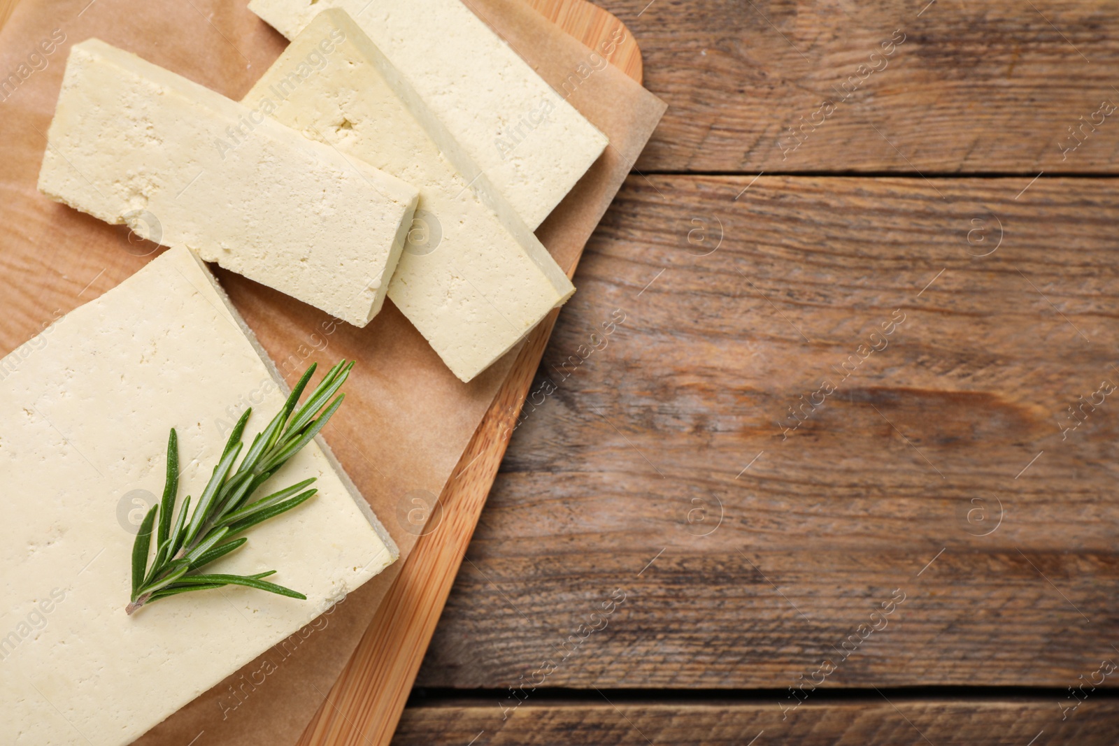 Photo of Delicious tofu with rosemary on wooden table, top view. Space for text