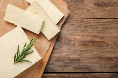 Photo of Delicious tofu with rosemary on wooden table, top view. Space for text