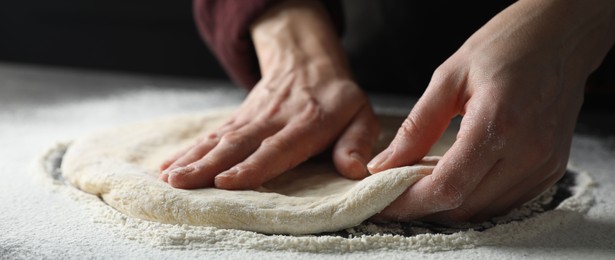 Photo of Woman kneading pizza dough at table, closeup