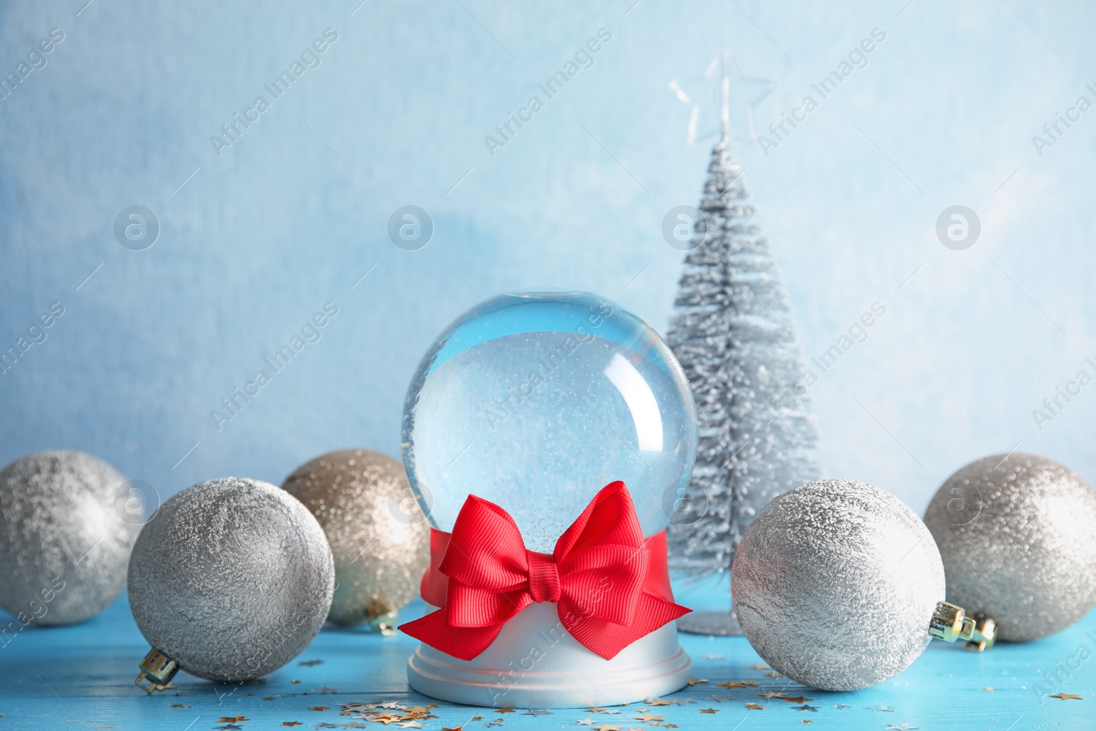 Photo of Empty snow globe with red bow and Christmas decorations on table