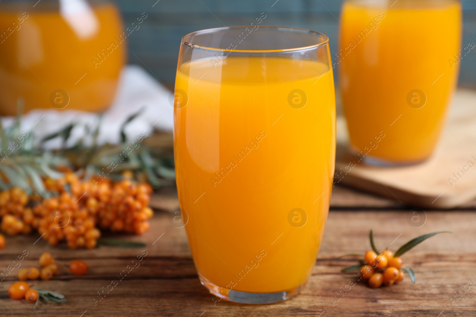 Photo of Sea buckthorn juice and fresh berries on wooden table, closeup