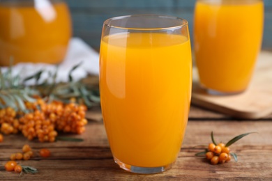 Sea buckthorn juice and fresh berries on wooden table, closeup