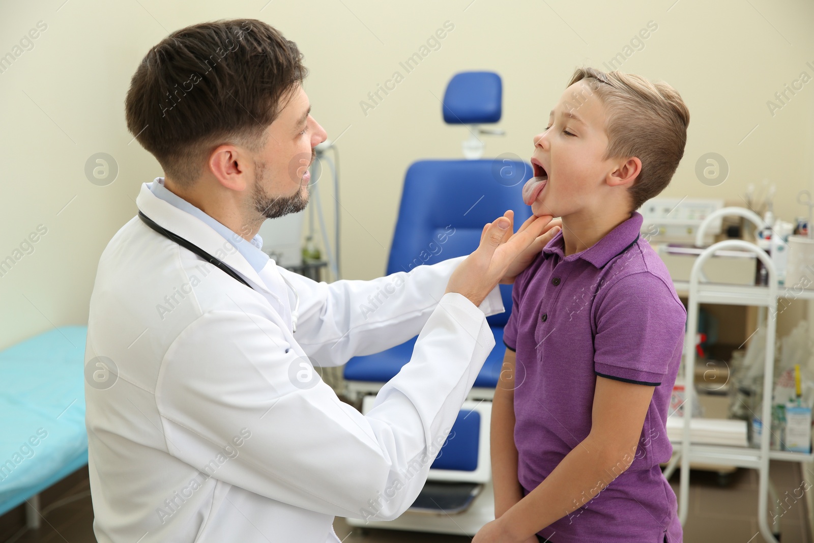 Photo of Male otolaryngologist examining little child in hospital