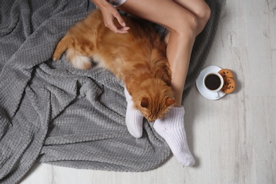 Woman with cute red cat and coffee on floor, top view