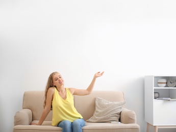 Young woman relaxing under air conditioner at home