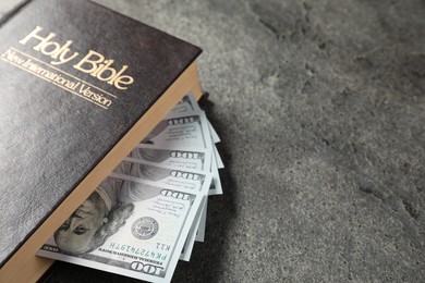 Photo of Holy Bible and money on grey table, closeup. Space for text